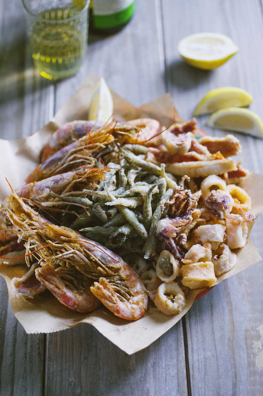 Fritto misto di pesce, servito su un vassoio con spicchi di limone 