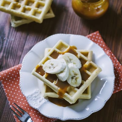 Waffle senza glutine, servito con un velo di salsa al caramello e banane a fette