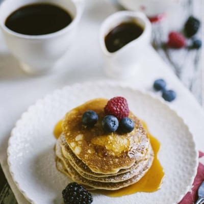 Pancakes senza glutine e latticini, guarniti con sciroppo d'acero e frutta fresca