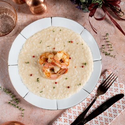 Risotto allo champagne e gamberi, decorato con pepe rosa in grani