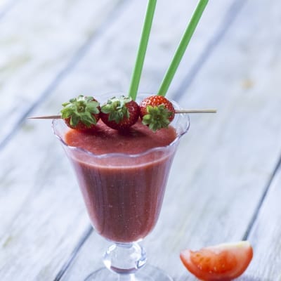 Smoothie di fragola, pomodoro e zenzero, servito con uno spiedino di fragole