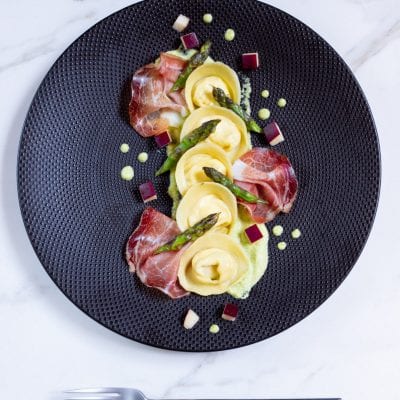 Cappellacci con ricotta, speck, mele e crema di asparagi pronto per l'assaggio