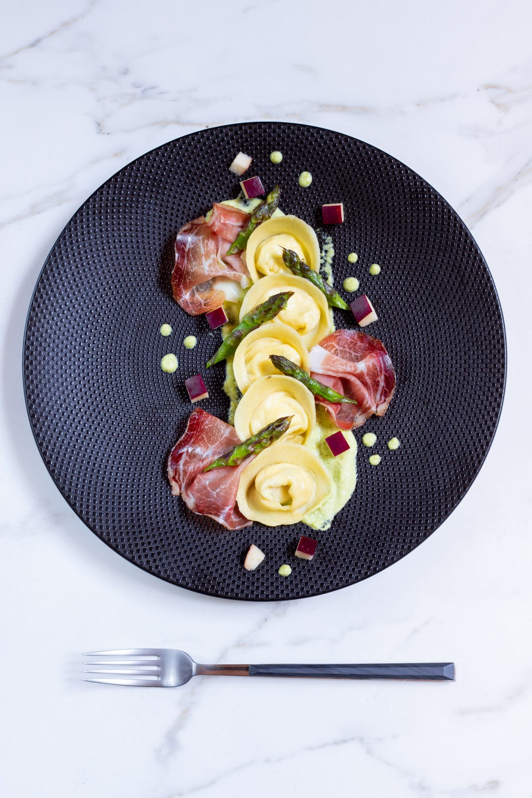 Cappellacci con ricotta, speck, mele e crema di asparagi pronto per l'assaggio