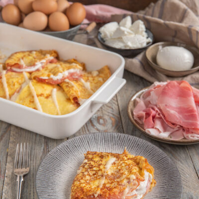 teglia con crespelle e porzione in primo piano