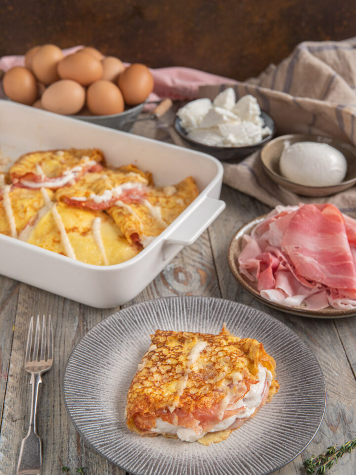 teglia con crespelle e porzione in primo piano