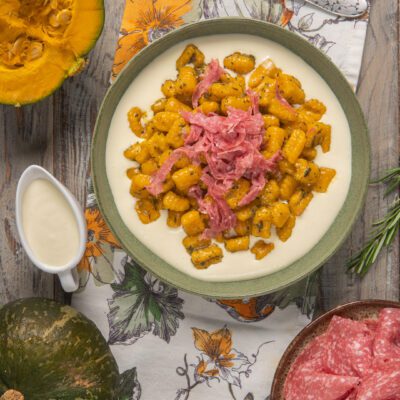 Gnocchi serviti sulla fonduta e decorati con salame tagliato a julienne