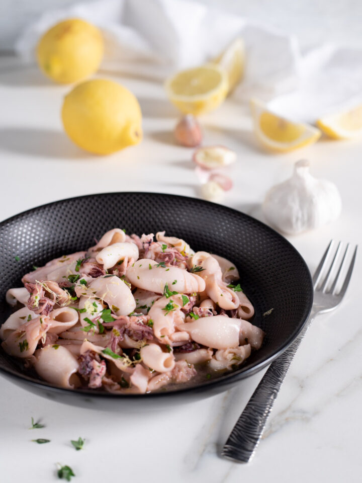 piatto di portata con calamaretti e limoni sullo sfondo