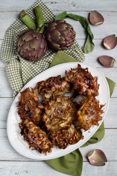 carciofi alla giudia su piatto di portata con carciofi freschi