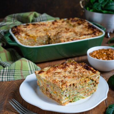 teglia di lasagne con una porzione su pèoatto di portata in primo piano