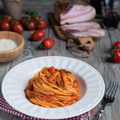 piatto di portata con spaghetti all'amatriciana e ingredienti
