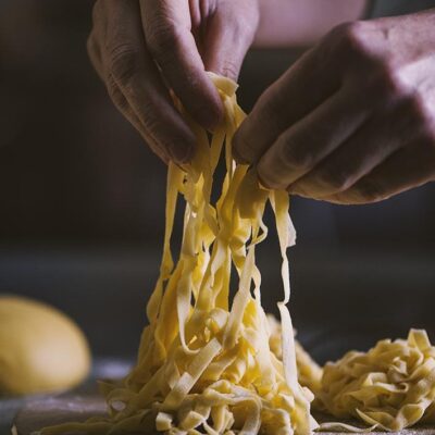 mani che lavorano tagliatelle fresche all'uovo