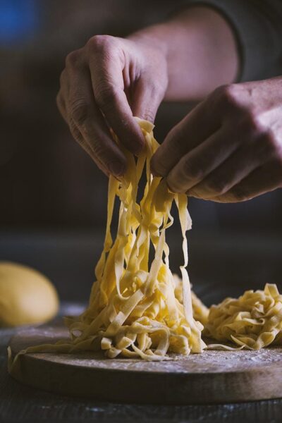 mani che lavorano tagliatelle fresche all'uovo