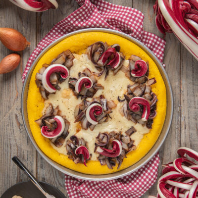 Torta di polenta con radicchio spadellato e fonduta di taleggio su tovaglia a quadretti rossi e bianchi