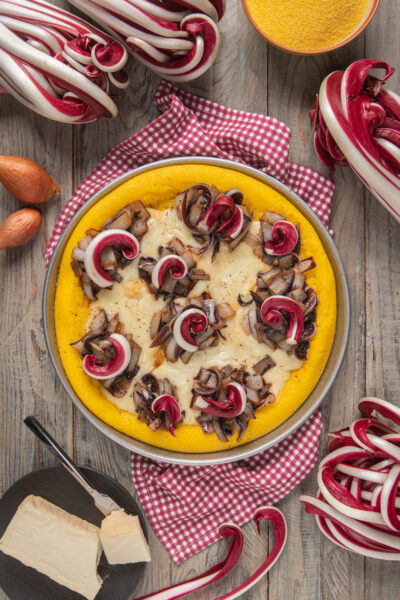Torta di polenta con radicchio spadellato e fonduta di taleggio su tovaglia a quadretti rossi e bianchi