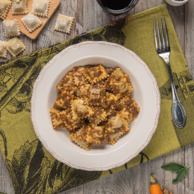 Agnolotti piemontesi con brasato su tovaglietta verde e forchetta argentata