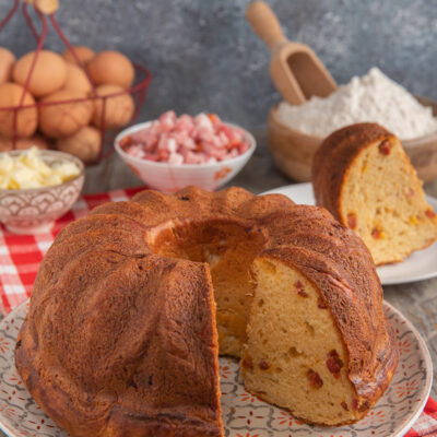 babà rustico salato su piatto da portata e ingredienti sullo sfondo