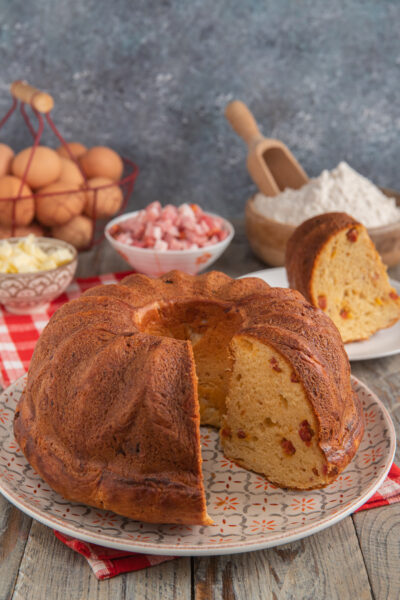babà rustico salato su piatto da portata e ingredienti sullo sfondo