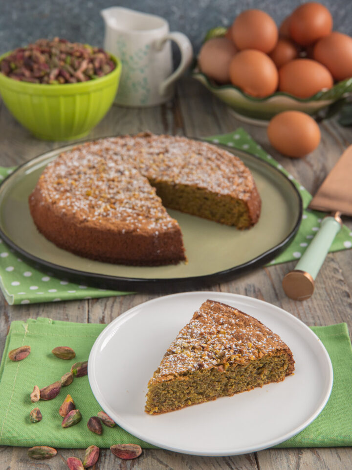 fetta di torta tenerina in primo piato con uova e pistacchi sullo sfondo