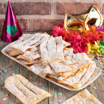 Chiacchiere con zucchero maschera di carnevale e stelle filanti