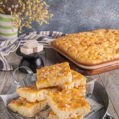 Focaccia genovese su tagliere con fette in primo piano e lievito a cubetti