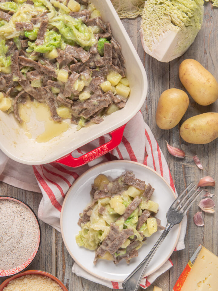 Pizzoccheri alla valtellinese con patate, aglio e formaggio, piatto singolo e teglia rossa