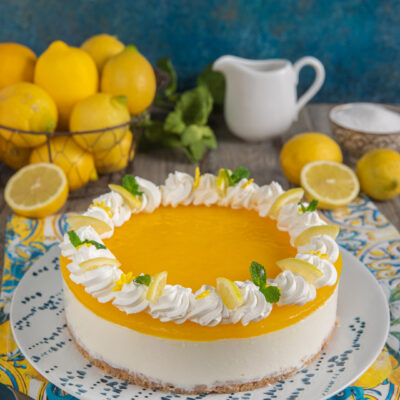 Cheesecake al limone su piatto bianco e azzurro, con cestino di limoni e paletta da dolci