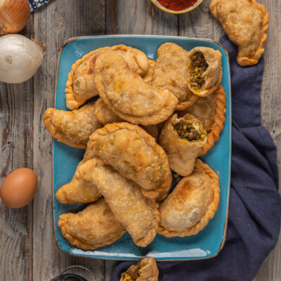 Empanadas argentine di carne su piatto rettangolare azzurro, con tovagliolo blu