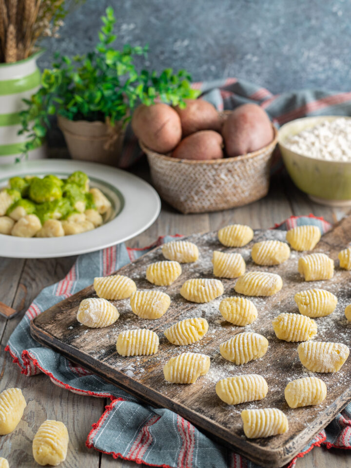 tagliere di legno con gnocchi di patate e piatto da portata con gnocchi e pesto