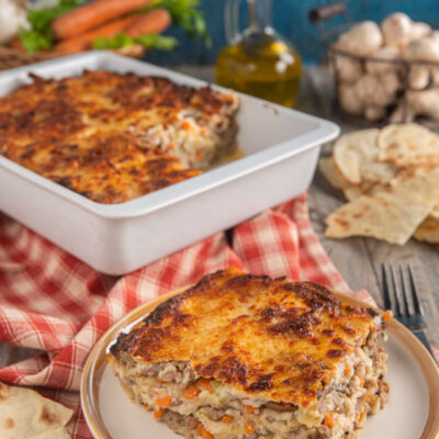 Lasagne di pane carasau con salsiccia e funghi con monoporzione e tovagliolo a quadretti bianchi e rossi