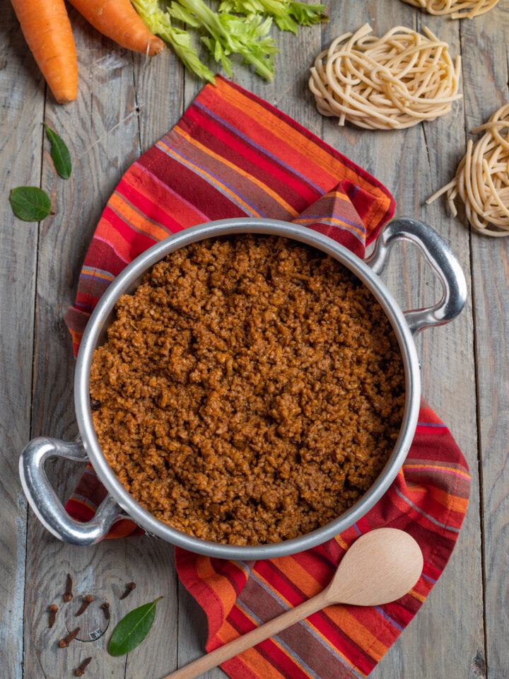 tegame con ragù alla bolognese, carote, sedane e nidi pasta cruda