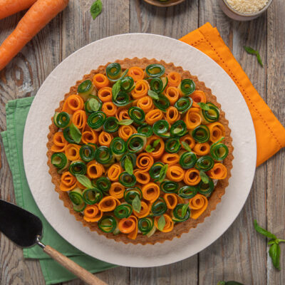 Torta salata con roselline di verdure, tovaglioli verde e arancione, paletta e carote