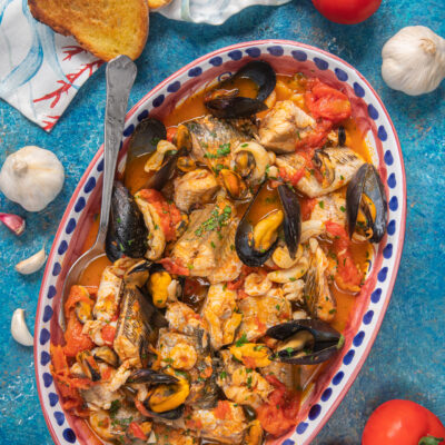 teglia con zuppa di pesce, pane, aglio e pomodori