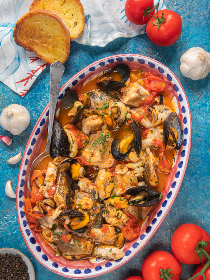 teglia con zuppa di pesce, pane, aglio e pomodori