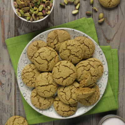 Biscotti al pistacchio su tovagliolo verde con pistacchi interi in ciotolina bianca