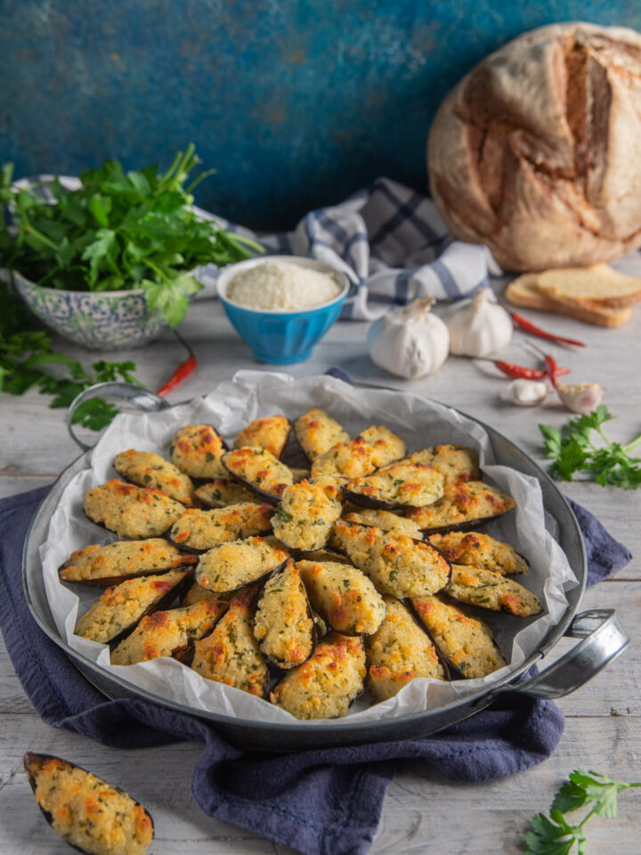 piatto da portata con cozze gratinate, prezzemolo, aglio, pane