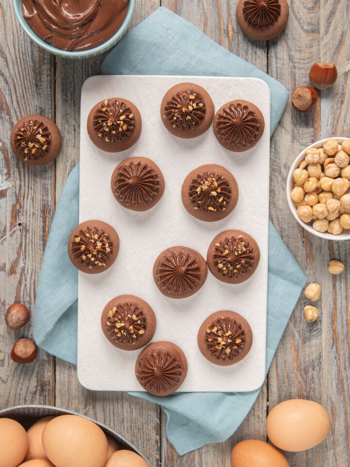 Nutellotti su vassoio rettangolare bianco, strofinaccio azzurro e ciotolina di nocciole sgusciate