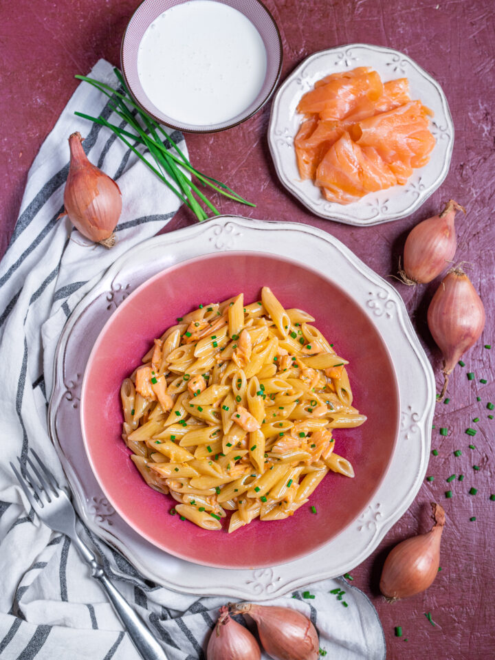 Piatto da portata con pasta panna e salmone e ingredienti intorno