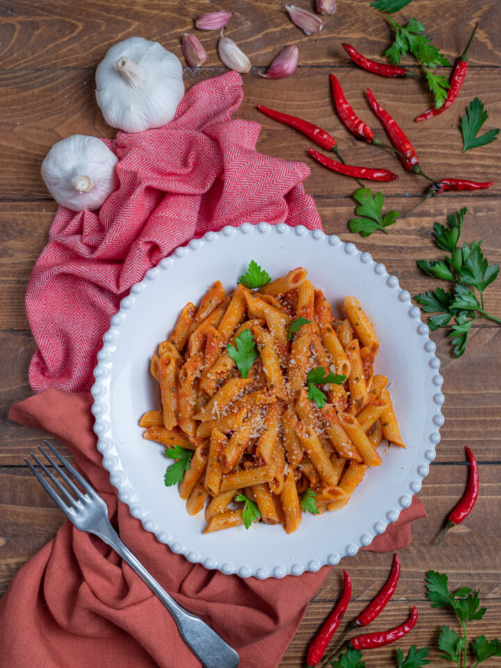 piatta da portata con penne all'arrabbiata, aglio e peperoncini freschi intorno