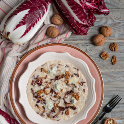 piatto da portata con risotto al radicchio e gorgonzola, cespo di radicchio crudo e noci intorno