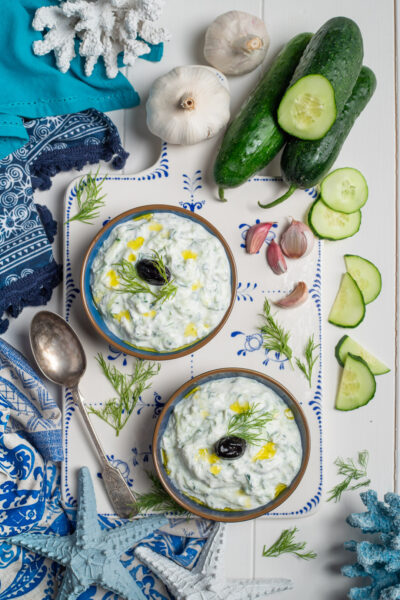 salsa tzatziki in ciotoline con olio e olive nere e cetrioli intorno