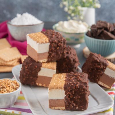 Biscotti gelato bigusto su vassoietto bianco rettangolare, con ciotoline di granella di nocciole, cioccolato, panna e mascarpone