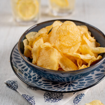 ciotolina con chips di patate e drink sullo sfondo