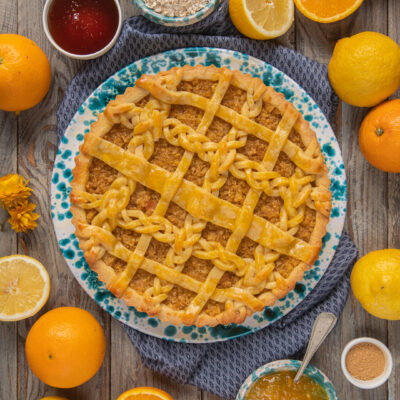 Marmalade treacle tart impattata su piatto bianco e azzurro, con attorno agrumi interi e tagliati