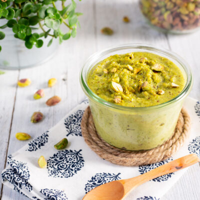 vasetto di vetro con pesto di pistacchi e cucchiaino di legno