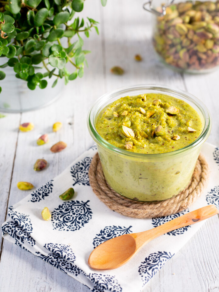 vasetto di vetro con pesto di pistacchi e cucchiaino di legno