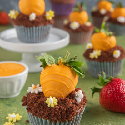 I cupcake carotina sono dolci al cioccolato ricoperti di glassa e decorati con fine carote realizzate con fragole e cioccolato bianco