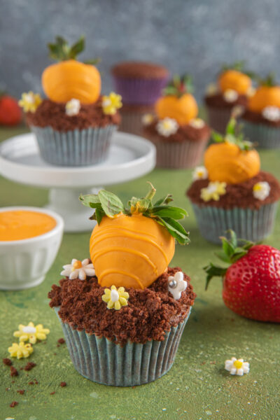 I cupcake carotina sono dolci al cioccolato ricoperti di glassa e decorati con fine carote realizzate con fragole e cioccolato bianco