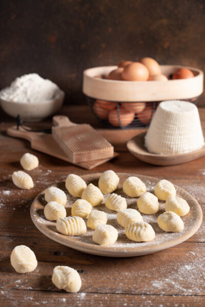 piatto da portata con gnocchi di ricotta e ingredienti sullo sfondo