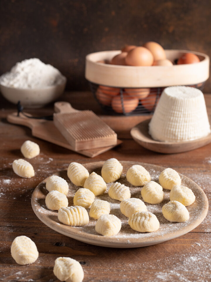 piatto da portata con gnocchi di ricotta e ingredienti sullo sfondo