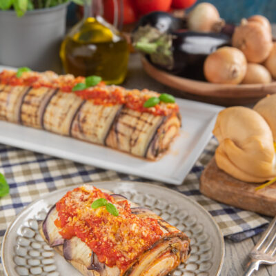 piatto con fetta di rotolo di parmigiana, scamorza, pomodori, basilico